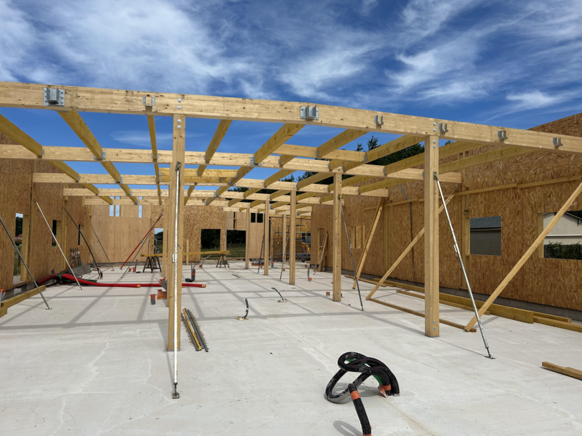 Vue extérieure d'une clinique vétérinaire en cours de construction mettant en avant sa charpente et son ossature en bois clair.